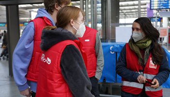 Drei Info-Point-Mitarbeitende mit Caritas-Westen bei der Einsatzplanung im Münchner Hauptbahnhof | © Caritas München-Freising