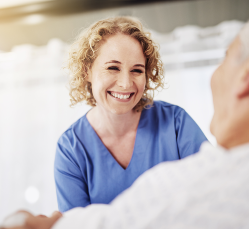 Pflegefachfrau der Caritas München lächelt Patienten freundlich an | © Cecilie Arcurs/Getty Images iStock 610435464