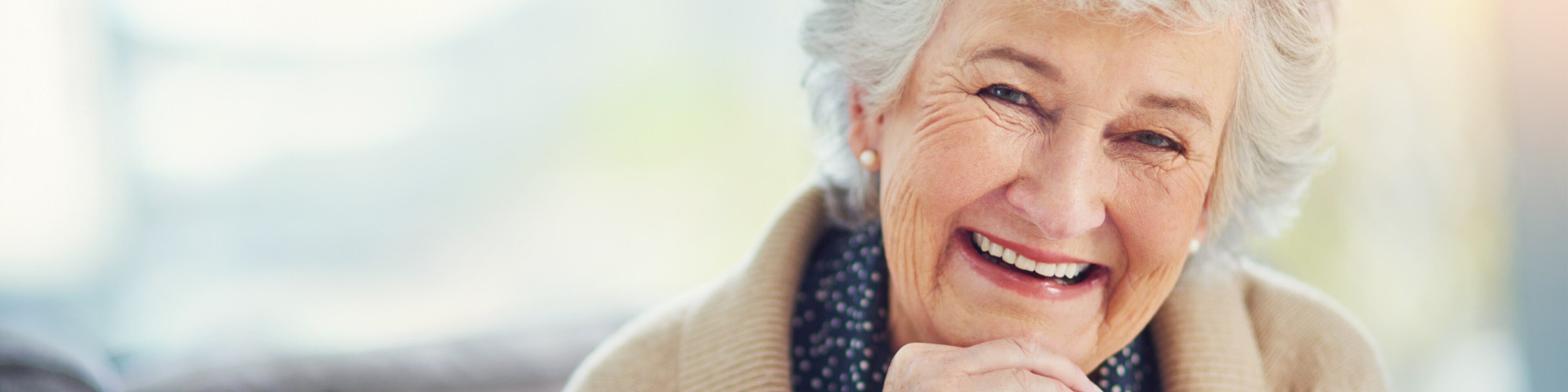 Porträt einer glücklichen älteren Frau, die sich zu Hause auf dem Sofa entspannt | © Cecilie Arcurs - iStock