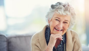 Porträt einer glücklichen älteren Frau, die sich zu Hause auf dem Sofa entspannt | © Cecilie Arcurs - iStock