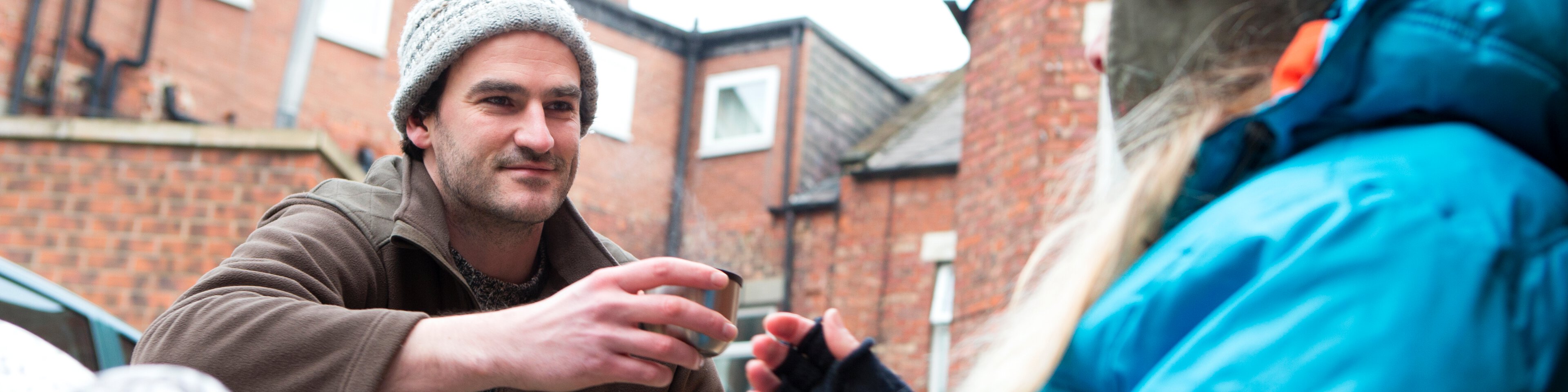 Ein Mann überreicht einen Obdachlosen eine Tasse Tee | © SolStock - Getty Images/iStockphoto